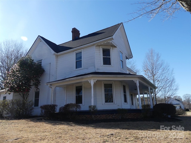 view of front of house featuring a porch, a front yard, and a chimney