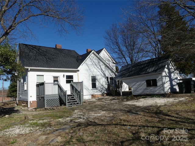 back of property with a shingled roof, a chimney, and a wooden deck