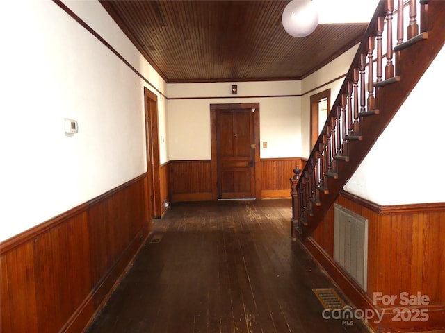 hall featuring wooden walls, visible vents, stairway, wainscoting, and dark wood-style floors