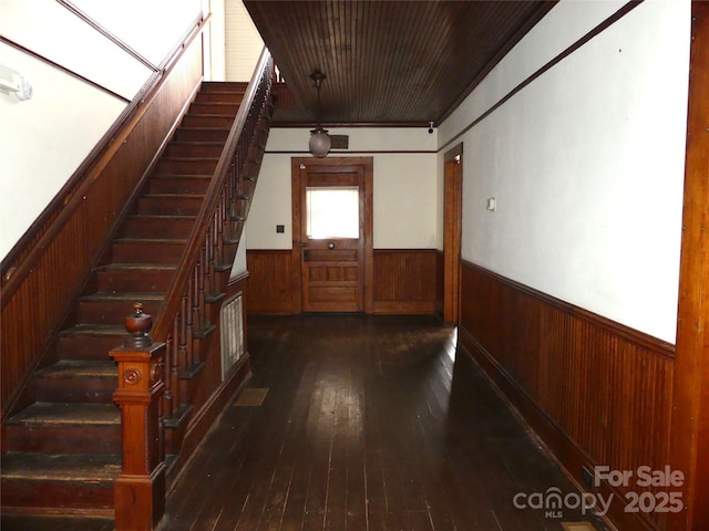 interior space featuring wood-type flooring, wainscoting, wood walls, and stairway