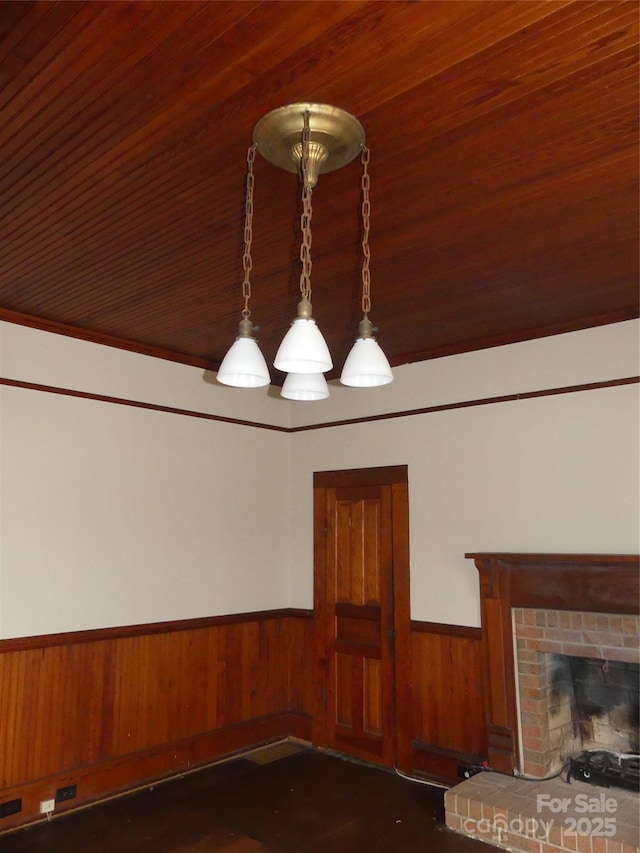 interior details featuring a wainscoted wall, a brick fireplace, and wooden walls