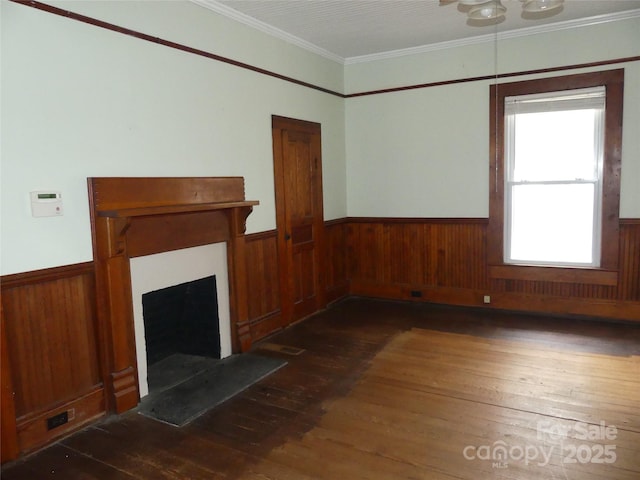 unfurnished living room with a fireplace with flush hearth, wainscoting, ornamental molding, and hardwood / wood-style floors