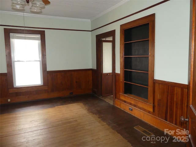 unfurnished room featuring wainscoting, hardwood / wood-style flooring, and wooden walls