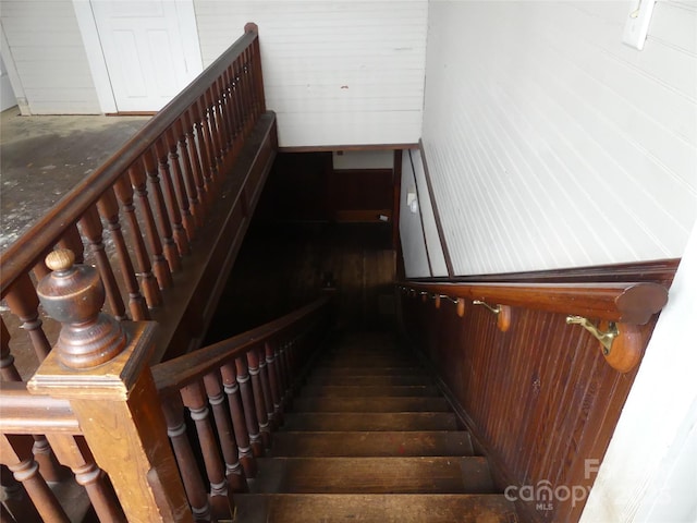 staircase featuring wooden walls