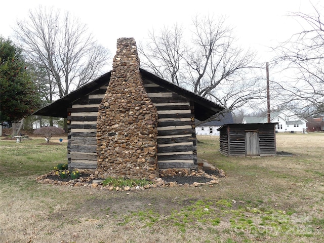 view of home's exterior with a yard, a storage unit, an outdoor structure, and log siding