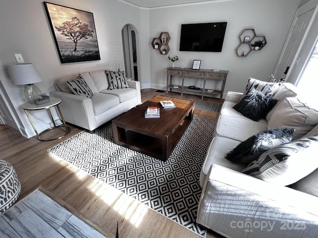 living room with arched walkways, wood finished floors, and baseboards