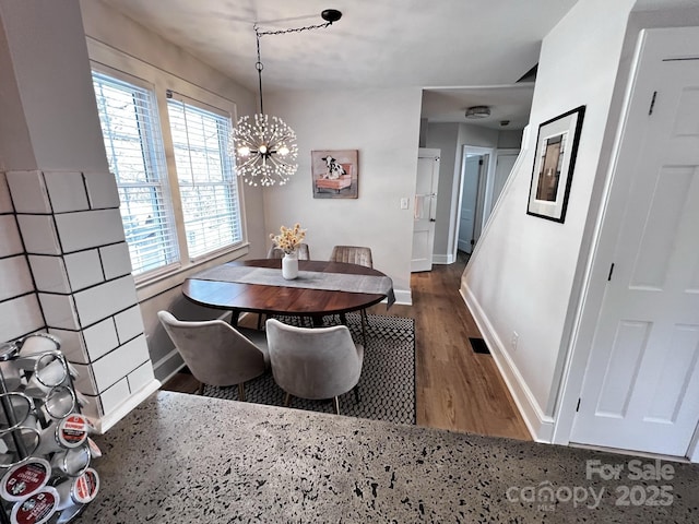 dining space with a notable chandelier, baseboards, and wood finished floors