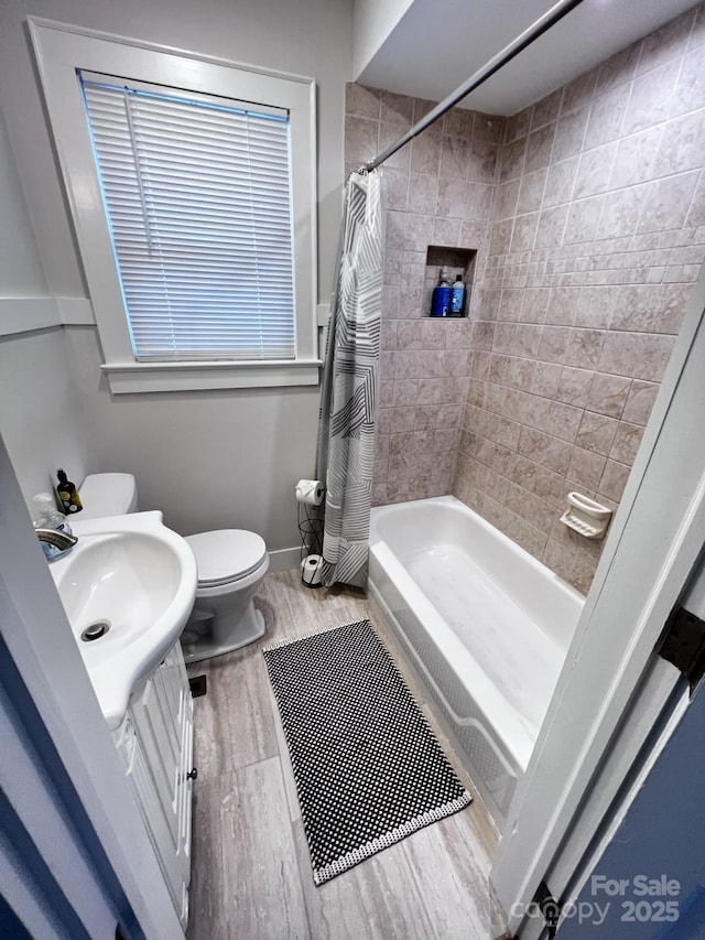 bathroom with shower / tub combo with curtain, toilet, vanity, wood finished floors, and baseboards