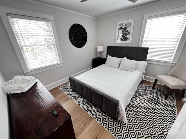 bedroom with crown molding, baseboards, and wood finished floors