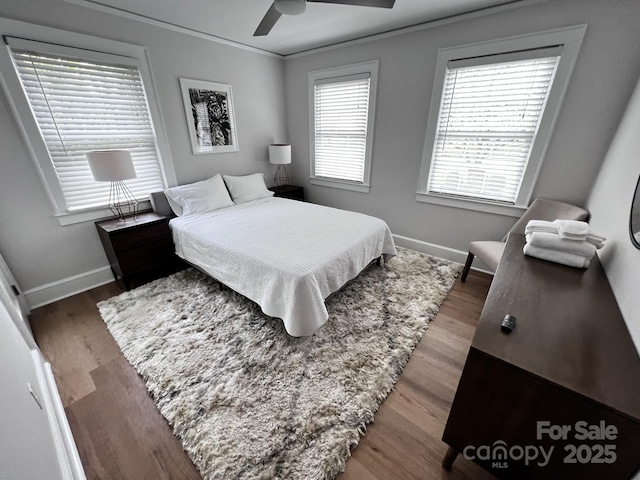 bedroom with crown molding, wood finished floors, a ceiling fan, and baseboards