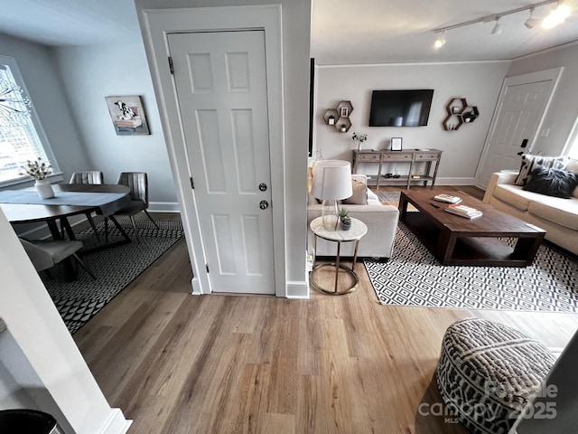 living room with crown molding, wood finished floors, rail lighting, and baseboards