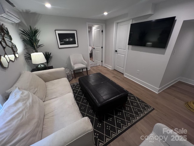 living room with recessed lighting, an AC wall unit, baseboards, and wood finished floors