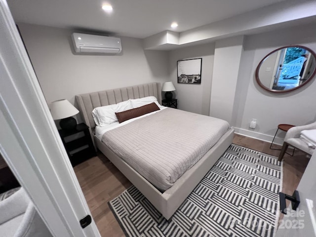 bedroom with recessed lighting, a wall mounted air conditioner, baseboards, and wood finished floors