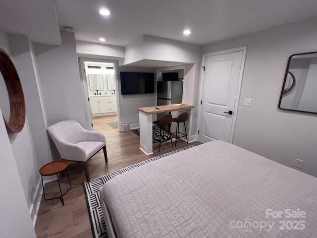 bedroom featuring baseboards, wood finished floors, freestanding refrigerator, and recessed lighting