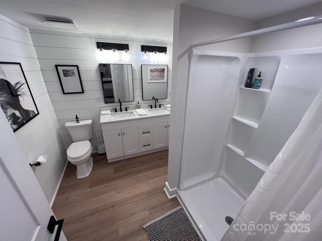 full bath with wood finished floors, a sink, toilet, and a shower stall