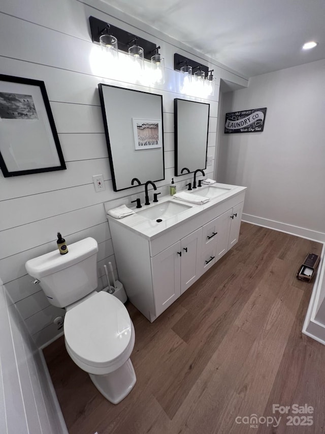 bathroom with double vanity, wood finished floors, a sink, and toilet