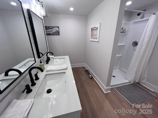 bathroom featuring wood finished floors, a stall shower, and a sink