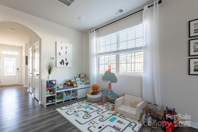 playroom with visible vents, arched walkways, and dark wood-type flooring