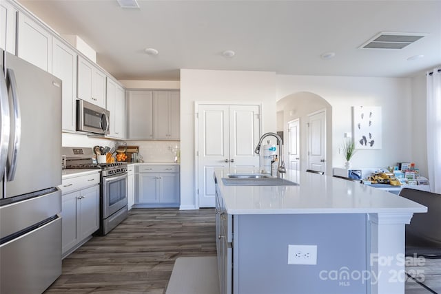 kitchen featuring a center island with sink, visible vents, stainless steel appliances, light countertops, and a sink