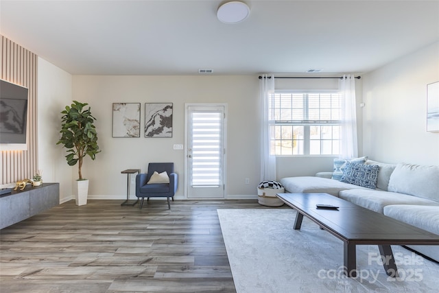 living area with visible vents, light wood-style flooring, and baseboards