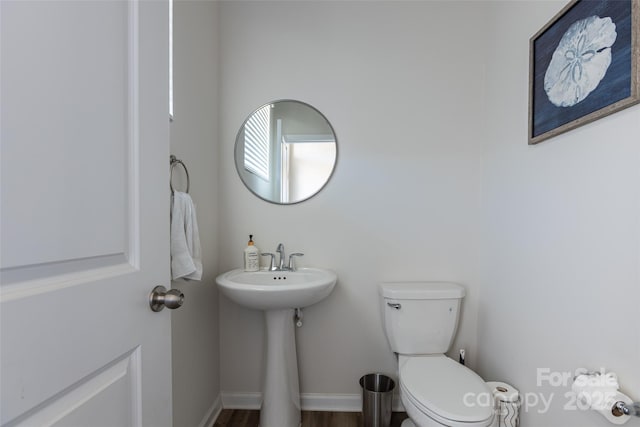 half bathroom featuring baseboards, toilet, and wood finished floors