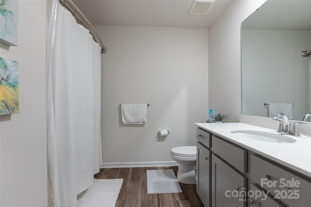 bathroom with baseboards, visible vents, toilet, wood finished floors, and vanity