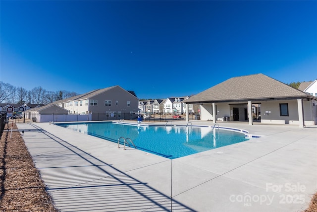 community pool with a residential view, a patio area, and fence