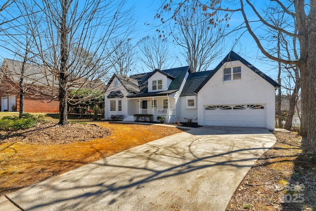 new england style home featuring a porch and concrete driveway