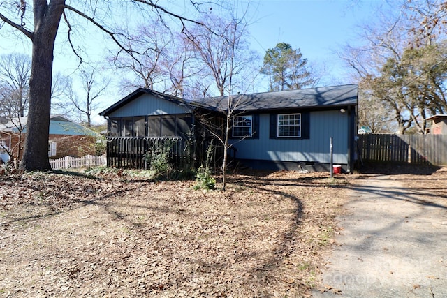 view of front of house featuring dirt driveway, fence, and a sunroom