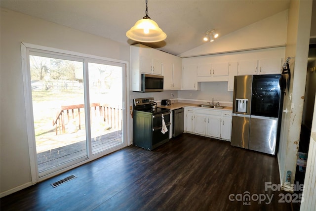 kitchen featuring decorative light fixtures, stainless steel appliances, visible vents, white cabinets, and a sink