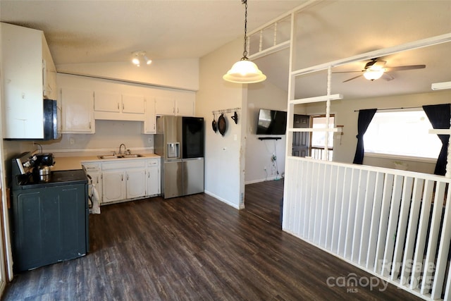 kitchen with stove, a sink, white cabinetry, vaulted ceiling, and stainless steel fridge