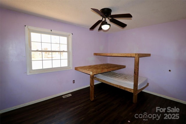 unfurnished dining area with baseboards, a textured ceiling, visible vents, and dark wood-type flooring