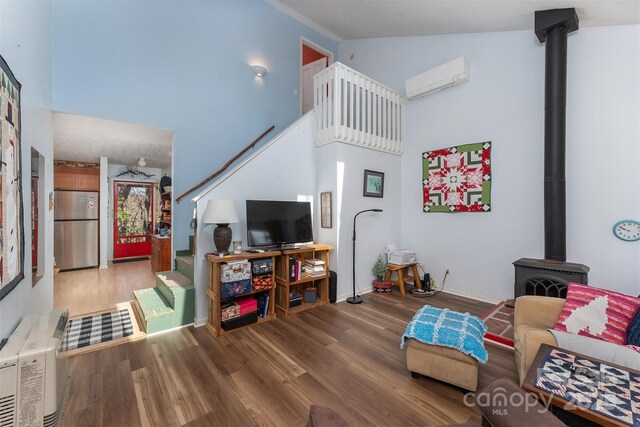 living room with high vaulted ceiling, wood finished floors, a wall mounted AC, a wood stove, and baseboards