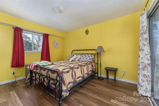 bedroom with wood finished floors, a textured ceiling, and baseboards