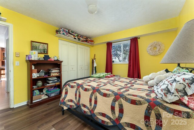 bedroom with baseboards, wood finished floors, a textured ceiling, and a closet
