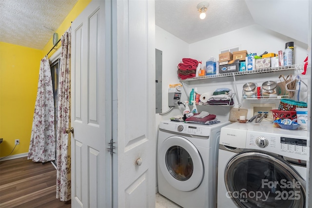 laundry room featuring electric panel, a textured ceiling, washing machine and dryer, wood finished floors, and laundry area