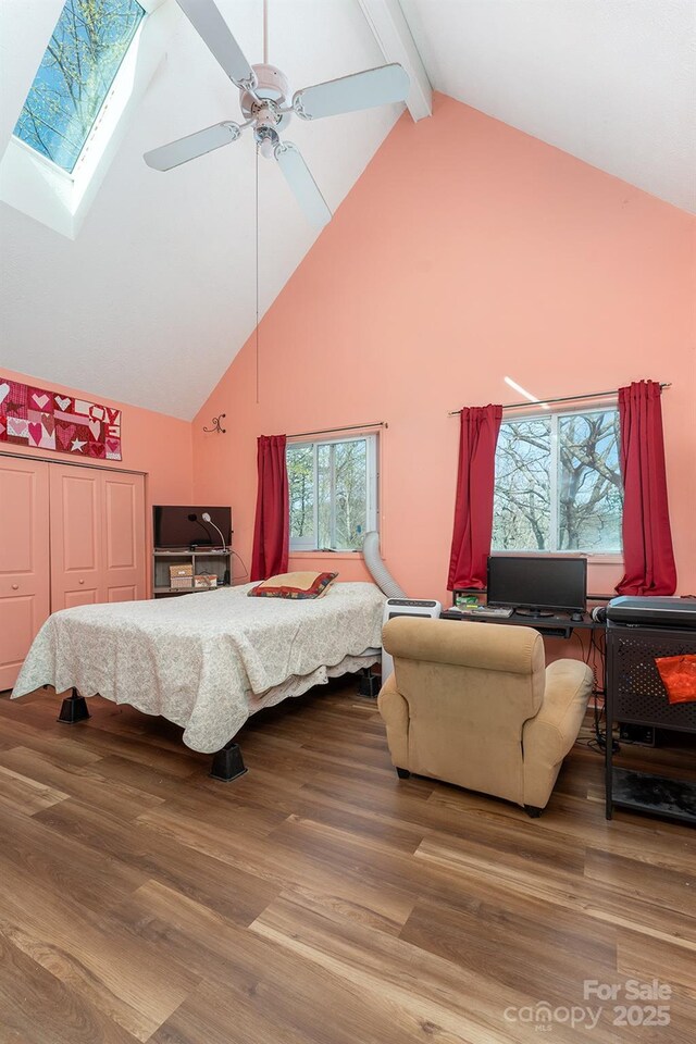bedroom with beam ceiling, wood finished floors, high vaulted ceiling, and a closet