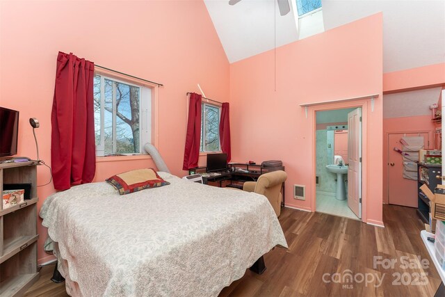bedroom with high vaulted ceiling, ensuite bath, and wood finished floors