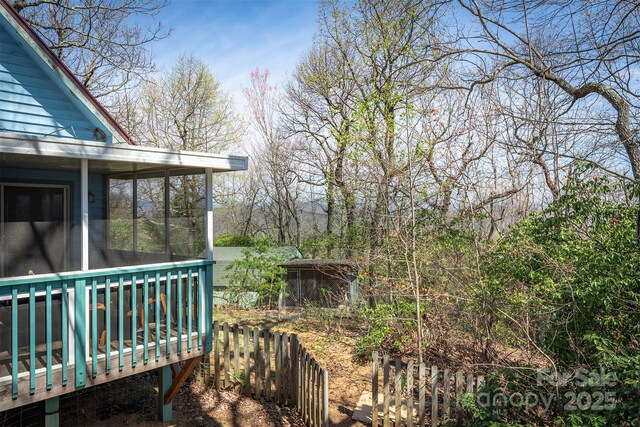 view of yard featuring a sunroom, fence, and a deck