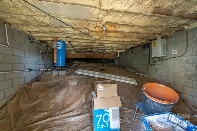 below grade area with tankless water heater and concrete block wall