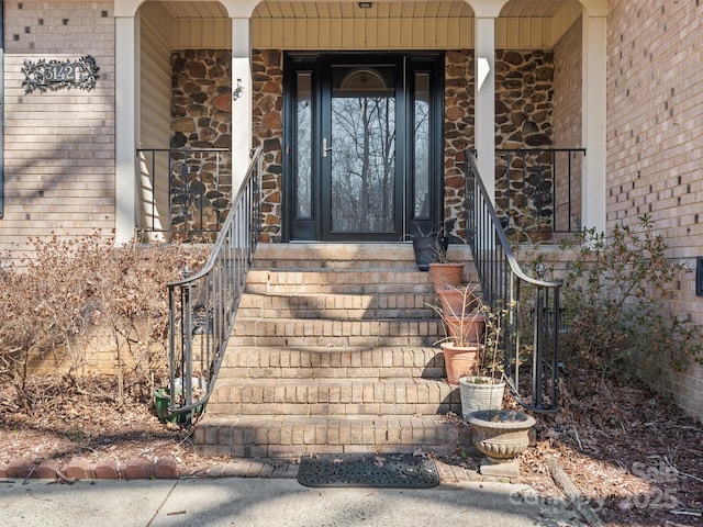 view of exterior entry with covered porch and brick siding