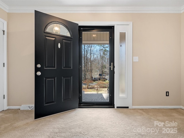 carpeted foyer entrance with ornamental molding, visible vents, and baseboards