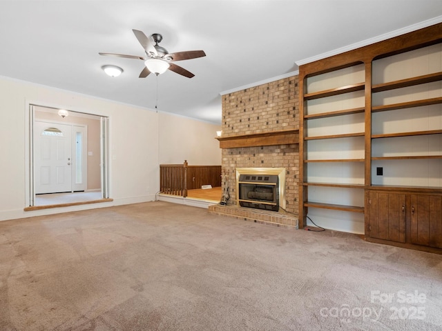 unfurnished living room featuring ceiling fan, carpet floors, a brick fireplace, and crown molding