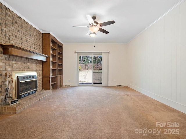 unfurnished living room with ornamental molding, light colored carpet, a fireplace, and ceiling fan