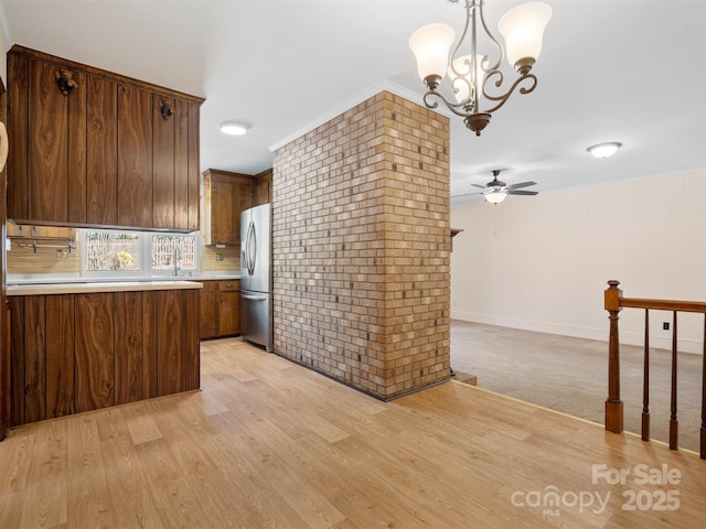 kitchen featuring brick wall, light countertops, hanging light fixtures, light wood-type flooring, and stainless steel refrigerator with ice dispenser