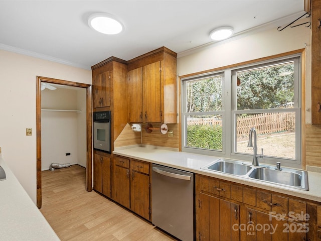 kitchen featuring stainless steel appliances, brown cabinetry, light countertops, and a sink