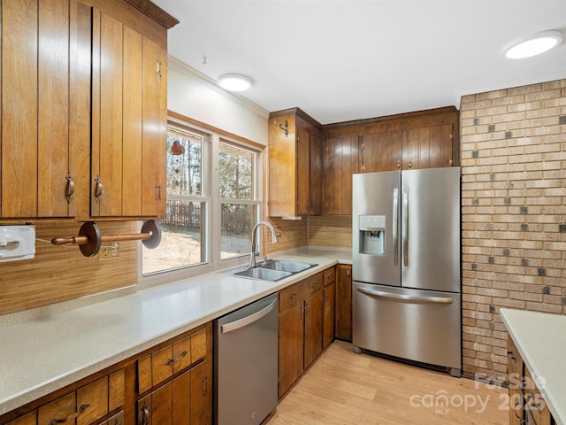 kitchen with light wood-style flooring, stainless steel appliances, a sink, and light countertops