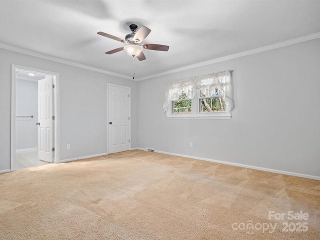 empty room with ceiling fan, carpet floors, ornamental molding, and baseboards