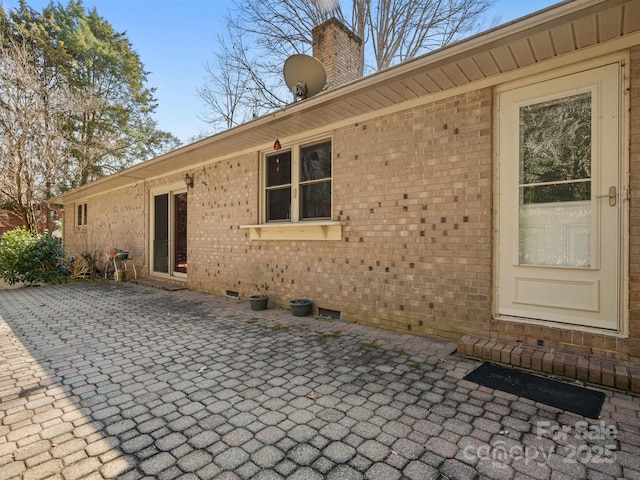 rear view of house featuring a patio area, brick siding, and a chimney