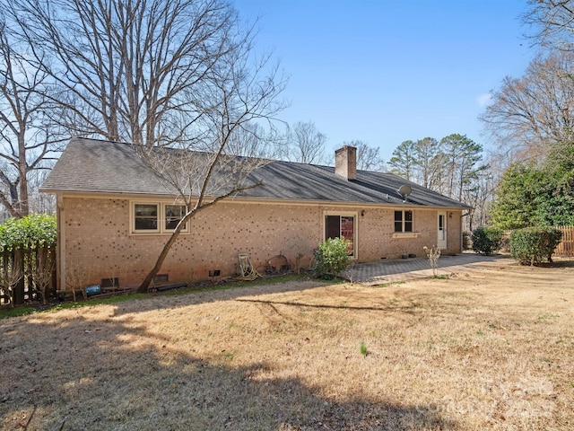 back of property featuring a chimney, crawl space, a yard, a patio area, and brick siding